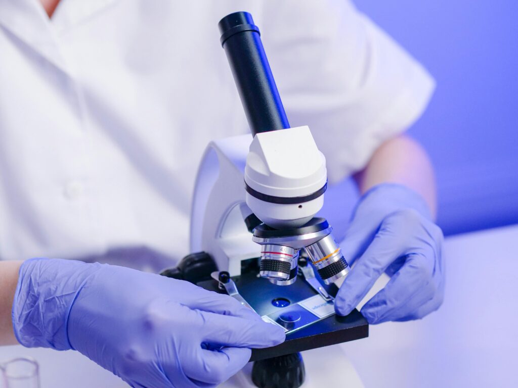 A person examining a sample through a microscope.